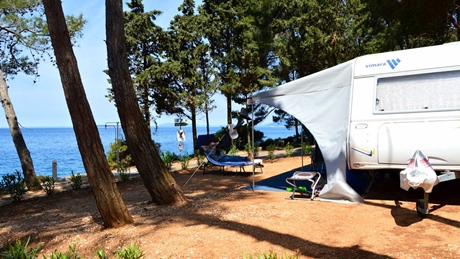 A campsite with a caravan and hammock overlooking the sea