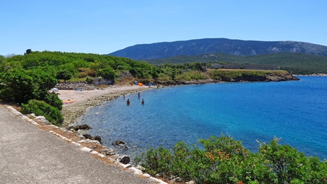 A scenic view of a beach on the island of Cres with clear blue water and green hills