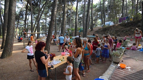 A group of people gathered in a forested area with tables and activities