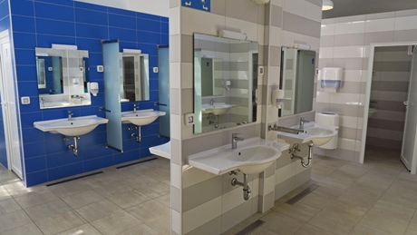 Modern public restroom with blue and white tiled walls and multiple sinks