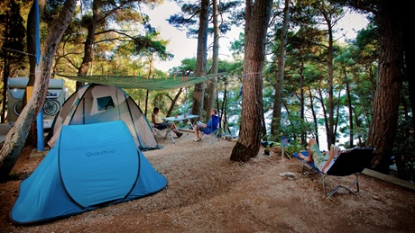 Camping area with tents and people relaxing among trees