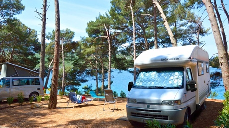 Camping area with motorhomes surrounded by trees near the sea on Cres