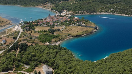 Aerial view of a coastal village on Cres Island with lush greenery and blue waters