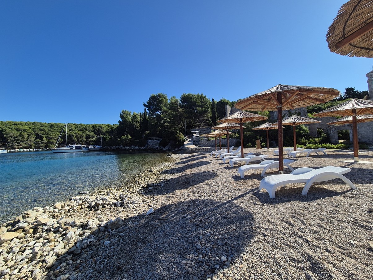 Kamienista plaża z leżakami i parasolami