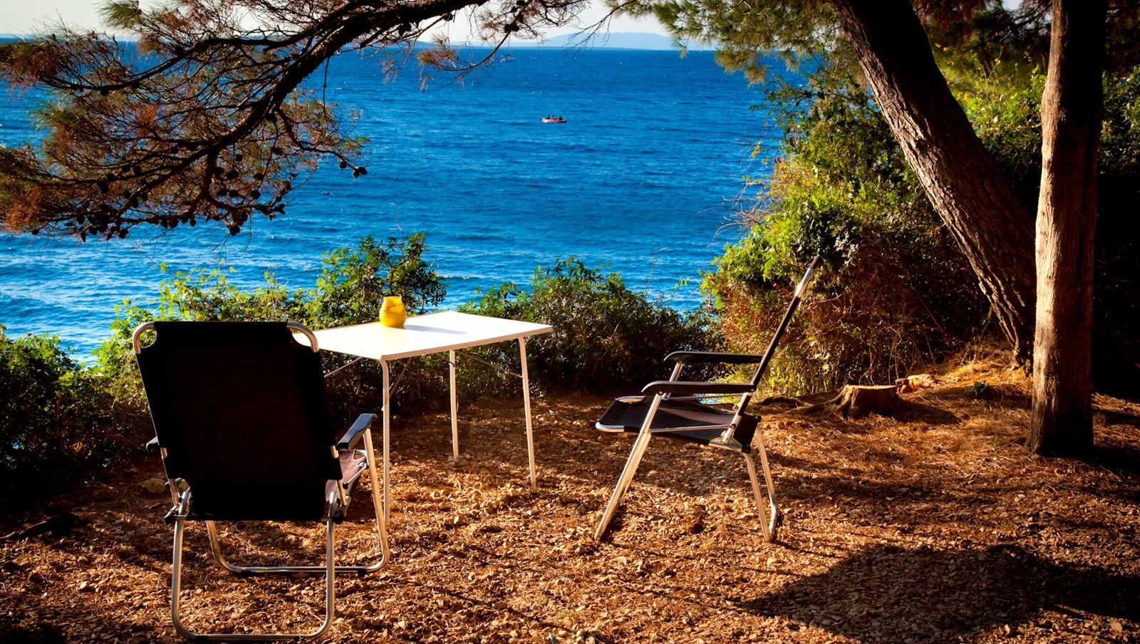 Zwei Stühle und ein Tisch mit Blick auf das Meer an einem sonnigen Tag