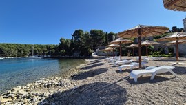 Šljunčana plaža s ležaljkama i suncobranima