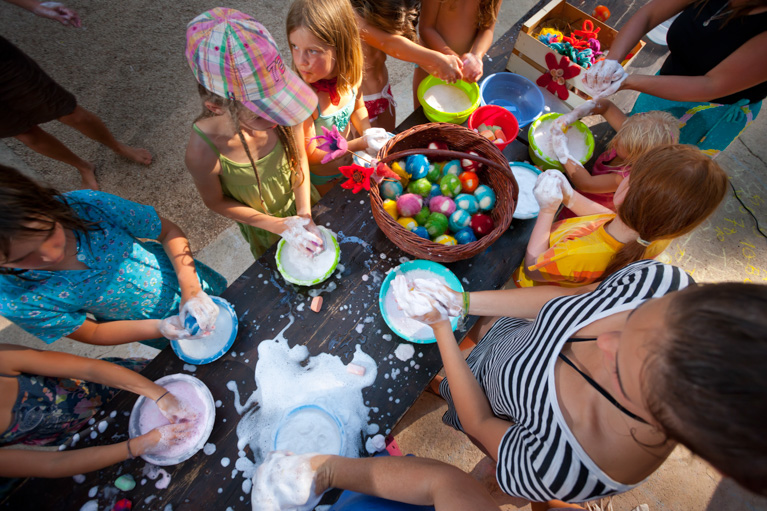 Children playing with colorful foam and eggs at a table