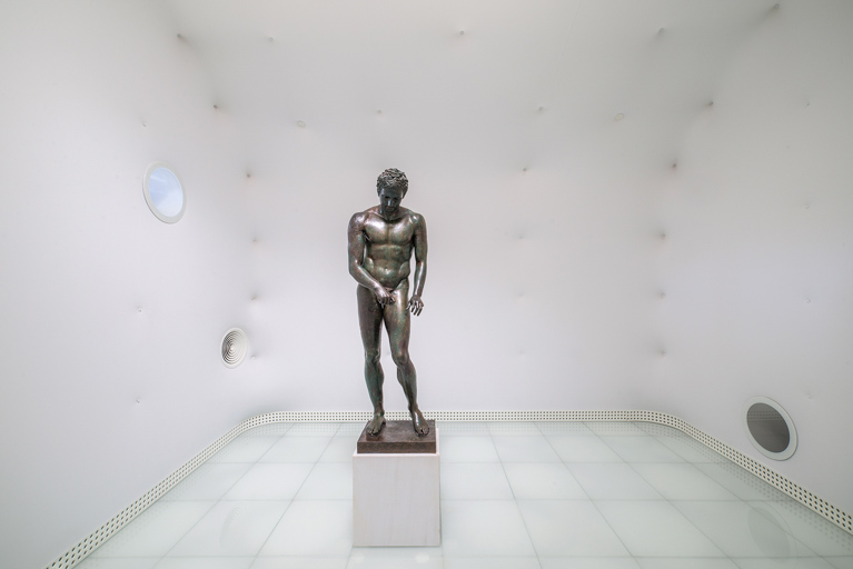 Statue of Apoxyomenos in a modern exhibition space